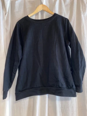 Svart basic sweatshirt - En enkel svart sweatshirt med rund halsringning och långa ärmar. Tröjan har ribbade muddar vid ärmslut och nederkant. Perfekt för en clean och avslappnad stil. Materialet ser ut att vara mjuk bomull eller bomullsblandning. Liten i storleken skulle säga den är storlek S/M. 