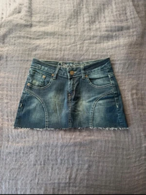 Blå lågmidjad jeanskjol  - Säljer en mörkblå jeanskjol från Ciggy wiggy med fransig kant och lågmidja. Kjolen har skönt material och skön passform! Bra i storlek också.