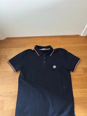 Mörkblå pikétröja från Moncler - Säljer min mörkblåa moncler piké, Pikén har aldrig andvänds. Det finns även NFC Scan på den