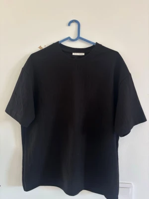 Svart oversized t-shirt från Weekday - En svart oversized t-shirt från ZARA med klassisk rund hals och korta ärmar. Perfekt basplagg som passar till allt och ger en clean look.