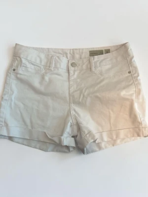 Vita shorts från vero moda storlek M - shorts från vero moda i fint använt skick. Klassisk modell med bälteshällor och knappstängning. Fickorna framtill är dekorativa (inte riktiga fickor), medan fickorna baktill är riktiga. Perfekta till sommaren. 
