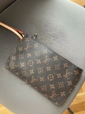 Clutch - Snygg mindre clutch plånbok. Plånboken har guldfärgad dragkedja och avtagbar handledsrem i läder med röda och gula detaljer. Perfekt för att hålla ordning på kort och kontanter. (Obs köpt utomlands) lite sliten som bild visar men väldigt fin kvalité. 