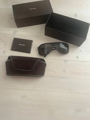 Tom Ford solglasögon - Snygga svarta solglasögon från Tom Ford med klassisk pilotform.  Kommer med originalfodral och box. Är lite trasiga på högra bågen går att fixa lätt kolla bild nr4. Nypris ligger på 400 euro vilket motsvarar cirka 4500kr! Perfekta för dig som vill ha stilrena och exklusiva solglasögon!