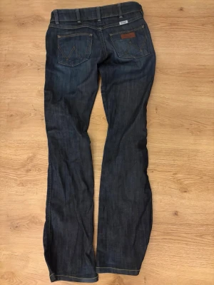 Lowwaist jeans med fina detaljer - Säljer för att de tyvärr inte passar. Aldrig använda av mig, endast tvättade efter att de blivit köpta här på Vinted i nytt skick.                     De är lowwaist och utsvängda i modellen Megan.  Mått:  Innerbenslängd 77,5 cm. Midja 34 cm med stängd knapp. Inte stretchiga.                                  W25 och L34 men inte helt säker vad det motsvarar för storlek, jag skrev in det som XS.  98% bomull