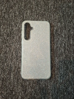 Glittrigt silverfärgat mobilskal - Snyggt mobilskal i glittrigt silver som ger din mobil en extra touch. Skalets yta är täckt av glitter och har en slimmad design med öppning för trippelkamera. Tillverkat i flexibel plast som skyddar mot repor och stötar. Skalet tillhör Samsung galaxy A55 5g
