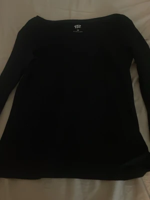 Svart långärmad topp från 157 - En enkel och stilren svart långärmad topp från 157. Toppen har en rund halsringning och är tillverkad i ett mjukt material som passar perfekt till olika outfits. Snygg att matcha med både jeans och kjol.