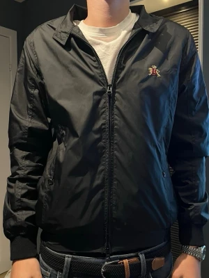   Baracuta England G10 vindjacka  - Säljer en klassisk Baracuta jacka i svart. Helt ny och i toppskick, använd ett fåtal gånger. Tidlös modell med stilren design som passar till det mesta.  ✔️ Original Baracuta ✔️ Made in England ✔️ Dragkedja + fickor ✔️               Perfekt för både vår och höst  Storlek: S. Skick: 10/10   Nypris ligger runt 4000 kr. Hör av dig vid frågor eller fler bilder!