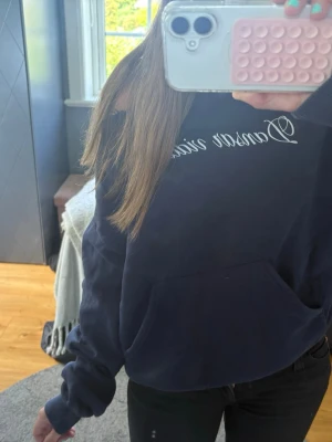 Mörkblå hoodie med textprint - Säljer en mörkblå hoodie med vit textprint. Ofshoulder tröja.