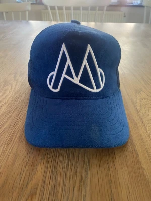 MAGGIORE UNLIMITED M LOGO BLUE CAP  - Unlimited M Logo Blue Cap från Maggiore är en stilren keps i bomullstwill med lätt böjd skärm. Den justerbara passformen och broderade loggan framtill gör den till ett självklart val för alla tillfällen – från skoldagar till häng med kompisar. 