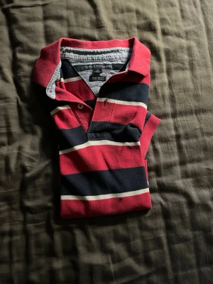 Pike tröja från Tommy hifiger - Säljer en pikétröja från Tommy hilfiger som är svart, vit och röd randig i storlek M