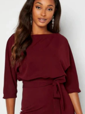 Vinröd jumpsuit med knytband - Vinröd jumpsuit med trekvartsärmar och smala ben. Modellen har ett matchande knytband i midjan och en lösare överdel som ger en snygg siluett. Tillverkad i ett mjukt, vävt tyg som känns bekvämt och stilrent. Köpt på Bubbleroom.