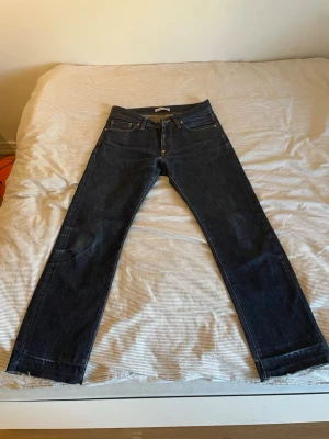 Raw denim  Acne Jeans - Säljer ett par raw denim mörkblå jeans från Acne med rak passform och fem fickor. Jeansen har råa kanter vid bensluten och är tillverkade i slitstark denim. Perfekta för en avslappnad och tidlös stil. (Midja: 39cm. Längd: 100cm) (Modell 177 cm) Priset är ej hugget i sten 😊