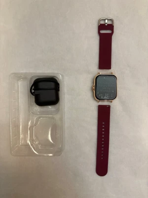 Smartklocka med vinrött silikonarmband - Snygg smartklocka med fyrkantig display och guldfärgad ram. Klockan har ett vinrött silikonarmband och levereras med laddningsetui och manual. Perfekt för dig som vill ha koll på notiser och hälsa direkt på handleden.