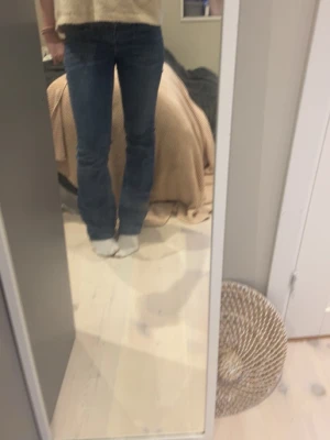 Blå bootcut jeans från Nelly - Säljer ett par blå bootcut jeans från Nelly med klassisk femficksdesign och dubbla knappar i midjan. Jeansen har en lätt tvättad look och är tillverkade i stretchigt denimtyg för en bekväm passform.