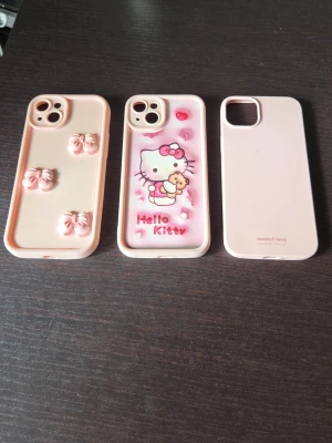 3-pack rosa mobilskal med rosetter & Hello Kitty - Säljer tre söta mobilskal i ljusrosa. Ett har 3D-rosetter, ett har Hello Kitty-motiv med små hjärtan och text, och det tredje är stilrent enfärgat. Alla är gjorda i mjukt silikonmaterial och passar perfekt för dig som vill ha gulliga och personliga skal.