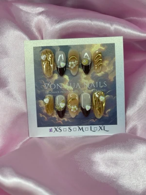 GoldenLatte (XS);Medium Almond - Unika press-on naglar i en medium mandelform. Designen har en mix av guld, brunt och nude med vita-blommor, pärlor och metallicdetaljer. XS: 14 mm, 11 mm, 11,5 mm, 10 mm, 8 mm , och varje nagel har en glansig finish med coola detaljer som swirl-mönster och hjärtan.