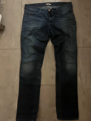 Mörkblå raka jeans från Wrangler - Säljer ett par mörkblå jeans från med raka ben och klassisk femficksmodell. Jeansen har snygga slitningar och kontrastsömmar, samt Wrangler logga på bakfickan. Perfekta för en avslappnad och trendig look. Storlek W30/L32