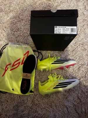 Adidas F50 Elite AG fotbollsskor - Säljer ett par Adidas F50 Elite AG fotbollsskor i neon-gult och svart med vita detaljer. Skorna har låg vikt, snörning och en aggressiv dobbsula för konstgräs. Ovandelen är tillverkad i syntetmaterial och levereras med originalpåse och extra innersula. Skorna är helt nya fick de av mitt lag men kan inte ha Adidas skor. Så är behov av försäljning så lägg prisförslag 
