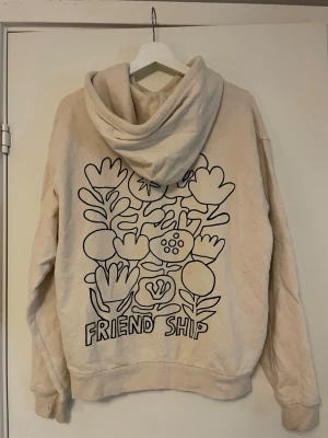 Hoodie med tryck från Levi’s - Jätteskön crémefärgad hoodie med tryck på ryggen och en liten blomma fram. Nästan helt oanvänd.