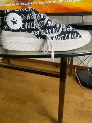 Converse Not Chuck Taylor svart/vit - Snygga Converse Not Chuck Taylor sneakers i svart med vit text och logga på sidan. Skorna har vita snören, vit sula och coolt grafiskt mönster över hela ovandelen. Klassisk rund tå och slitstark gummisula. Perfekta för dig som vill sticka ut med din stil.