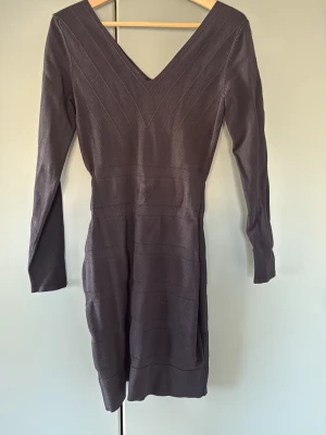 Mörkgrå stickad klänning Mango - Svart kort klänning från Mango med v-ringning både fram och bak. Klänningen har lång ärm. Klänningen har en kroppsnära passform och subtila ribbade detaljer som ger en snygg struktur. Perfekt för dig som gillar enkel men stilren design. Storlek M men skulle mer säga S