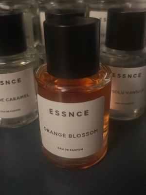 ESSNCE Orange Blossom Eau de Parfum - Fräsch parfym från ESSNCE med doft av orange blossom. Kommer i en rund glasflaska med svart lock och stilren vit etikett. Vätskan har en varm orange ton som ger en lyxig känsla. Perfekt för dig som gillar blommiga och fruktiga dofter.
