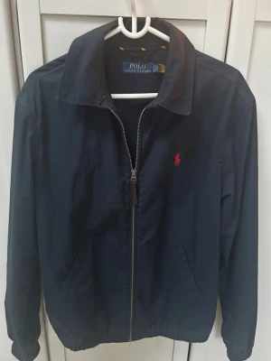 Ralph Lauren jacka - Säljer en klassisk marinblå jacka från Polo Ralph Lauren med dragkedja och röd broderad logga på bröstet🔥 Använd endast ett fåtal gånger! Nypris: 1800kr Mitt pris: 699                                       Hör av dig vid minsta lilla fundering😊pris ej hugget i sten. Skickar inom 1 dag
