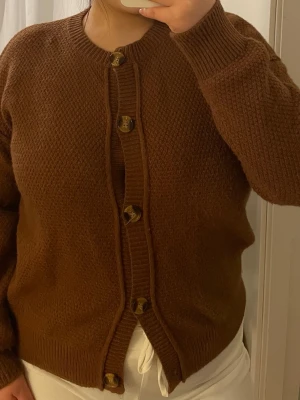 Brun stickad kofta med knappar - Mysig brun stickad kofta med grov struktur och stora bruna knappar framtill.                          Använd några gånger.                                    Leverans med Instabox eller mötesplats. 