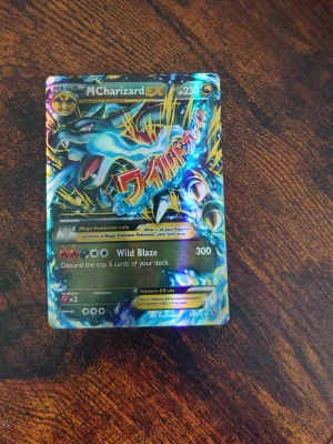 Pokémonkort Mega Charizard EX - Säljer ett samlarkort från Pokémon, Mega Charizard EX #230. Kortet har en glittrig yta med färger i blått, gult och svart samt japansk text och coola effekter. Perfekt för dig som vill utöka din Pokémonkort-samling.