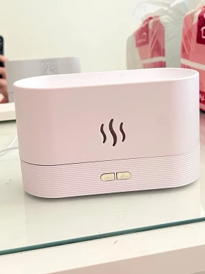 Vit luftfuktare med USB-anslutning - Minimalistisk vit luftfuktare i plast med rundade hörn och två knappar på framsidan. Har en dekorativ ångsymbol och drivs via USB. Perfekt för att förbättra luftfuktigheten i rummet och skapa en fräschare miljö.