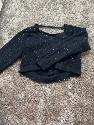 Svart stickad tröja med glitter - Mysig svart stickad tröja från Gina Tricot med glittriga detaljer. Tröjan har rund halsringning och är perfekt för dig som gillar lite extra bling i vardagen. Passar dig som vill ha en enkel men ändå festlig look.