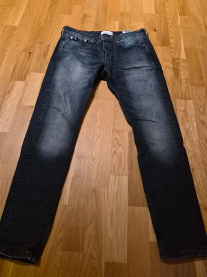 Mörkblå Calvin Klein jeans straight fit - Säljer ett par mörkblå jeans från Calvin Klein med straight fit och klassisk femficksmodell. Jeansen har snygga slitningar framtill och diskret CK-logga bak i midjan. Tillverkade i denim med en cool tvättad look. Jeansen är använda max 3 gånger. Dem är väldigt tjocka i materialet 