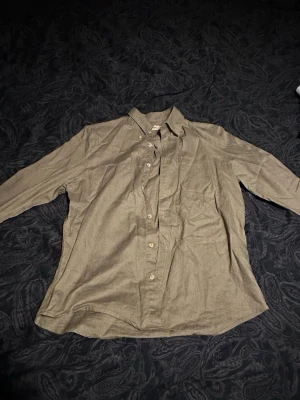 Beige linneskjorta med knappar - Snygg beige skjorta i linne med klassisk krage och knäppning framtill. Skjortan har långa ärmar med manschett och knappar vid ärmslut. Perfekt för en avslappnad men stilren look.