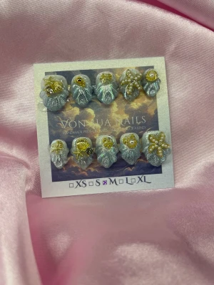 RoyalOpal (M);Short Almond - Unika handgjorda mermaid press-on naglar i skimrande silver med 3D-dekorationer i guld och pärlor. Naglarna har en kort, mandel form och är handgjorda med detaljer som snäckor, stjärnor och små pärlor för en lyxig look. Perfekt för dig som vill sticka ut med något extra.M: 16 mm, 12 mm, 12,5 mm, 11,5 mm, 10 mm