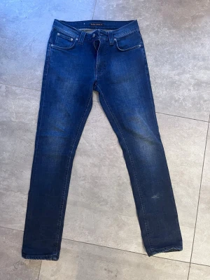Nudie Jeans - Lean Dean "Deep Cobalt" (W30 L32) - Säljer ett par superfina Nudie Jeans i modellen Lean Dean, tvätten heter "Deep Cobalt". Det är en klassisk slim fit-modell som smalnar av från knät och neråt, vilket ger en riktigt snygg siluett. Modell: Lean Dean Storlek: W30 / L32 Färg: Deep Cobalt (en djup, snygg mörkblå ton med lätt tvättad finish) Skick: Jättefint begagnat skick! Det finns en mycket svag fläck (se första och andra bilden), men den är inget man lägger märke till vid användning. I övrigt väl omhändertagna. Passa på att fynda!