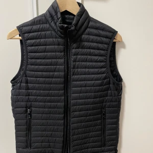 Emporio Armani Dunväst - En minimalistisk och högt kvalitativ svart dunväst från Emporio Armani i nyskick.