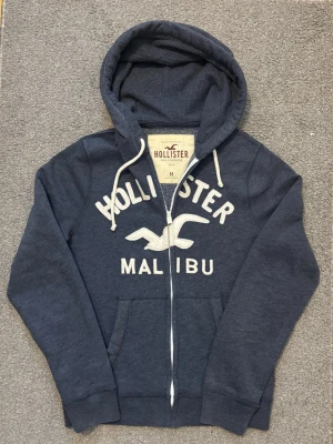 Vintage Hollister Zip-Hoodie - Sjukt fet Hollister zip hoodie som är mycket eftertraktad | Mycket bra skick | Storlek M | Längd ≈ 69cm , Bredd armhåla-armhåla ≈ 54cm | Modell 175cm, 68kg | Hör av vid funderingar!