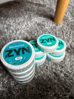 ZYN Menthol & Spearmint - Flera dosor ZYN nikotinpåsar i smakerna Menthol Ice och Spearmint. Dosorna är vita med turkos etikett och text, i slim-format. Perfekt för dig som gillar fräscha smaker och diskret användning.