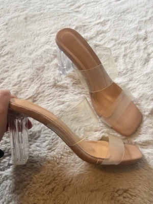 Genomskinliga klackar  - Snygga pumps med transparenta remmar och klack i akryl-look. Skon har en beige innersula och fyrkantig tå, vilket ger en modern vibe. Perfekta för dig som gillar stilrena och trendiga skor med en twist. Extremt sköna (kan ha i flera Tim). 