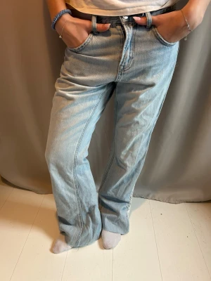 Ljusblå utsvängda jeans med spetsdetalj - Säljer ett par ljusblå jeans med rak passform och låg midja. Jeansen har en unik spetsdetalj längs bensidan och klassiska fem fickor. Tillverkade i denim med bälteshällor och knappgylf. Perfekta för en trendig och avslappnad look. 🩵Midjemåttet är 40cm rakt över och innerbenslängden är 78cm🩵