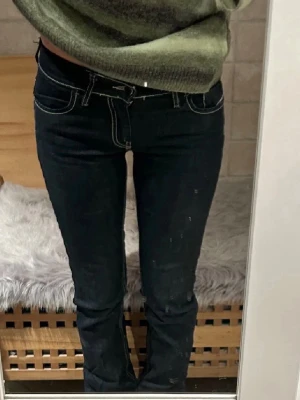 Mörkblå Diesel jeans  - Säljer ett par mörkblå bootcut jeans med vita kontrastsömmar och klassiska bakfickor. Jeansen har låg midja och smal passform upptill som går ut i en lätt utsvängd benvidd.