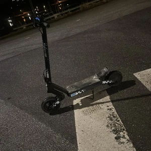 Svart elsparkcykel med mönster - Säljer en svart elsparkcykel med vita rutiga detaljer på sidan och sportig design. Modellen har bred fotplatta, stora hjul och högt styre. Perfekt för dig som vill ta dig fram snabbt och smidigt i stan. Laddningsuttag och display finns på styret. Kommer med laddare. Det finns inget frambroms så det är en elbroms här och bakbromsen funkar perfekt. Helst bo på Stockholm