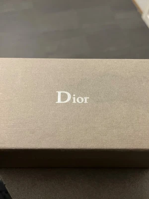 Dior solglasögon med originalask - Säljer ett par exklusiva solglasögon från Dior, levereras i originalask och förpackning. Perfekt accessoar för dig som vill ha en lyxig och trendig look. Klassisk design och hög kvalitet från ett av världens mest ikoniska modehus.