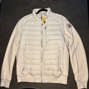 Vit pufferjacka från Parajumpers - Snygg vit hybridjacka från Parajumpers med quiltad front och mjuka ärmar. Jackan har dragkedja, hög krage med gul detalj och logga på ärmen. Perfekt för lager-på-lager och streetwear. Materialmix av fleece och puffer för extra komfort. Iprincip aldrig använd, nytt skick enligt bilderna. Har kvitto och extra knappar som kom med vid köp. Hör av er vid frågor.