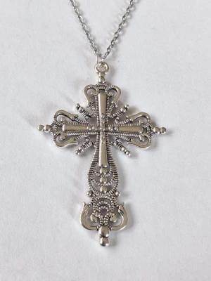 Detaljerat silverfärgat korshalsband - halsband med ett stort kors i silverfärgad metall. Korset har intrikata mönster och små kuldetaljer som ger en vintagekänsla. Hängs i en tunn kedja. Perfekt för dig som gillar unika smycken med mycket detaljer. Materialet rostfritt stål. 