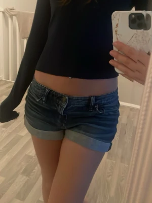 Blå denimshorts med upprullad kant - Snygga blå jeansshorts med upprullade benslut och klassisk femficksdesign. Shortsen har låg midja och är storlek M. Dom är från hm! 