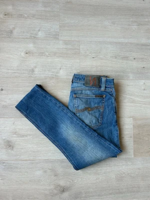Blåa Nudie Skinny Lin Jeans Storlek W28 L34 - Fina Nudie Jeans i blå färg. Jeansen är i mycket bra skick och sparsamt använda. |  Äkta som allt annat jag säljer! ✅ |  Storlek: W28 L34 | Skick: Mycket Bra Skick | Färg: Blå | Märke: Nudie | Modell: Jeans |   Hör gärna av dig vid frågor så svarar jag så fort jag kan! 😁 |  (SKU - 111)