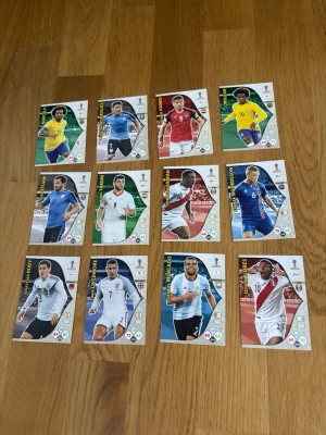 Panini VM 2018 fotbollssamlarkort - Säljer ett set med 12 officiella Panini Adrenalyn samlarkort från FIFA World Cup Russia 2018. Korten har färgglada motiv av olika fotbollsspelare i landslagsdräkter och är tryckta på glansigt papper. Perfekt för dig som gillar fotboll och samlarprylar.