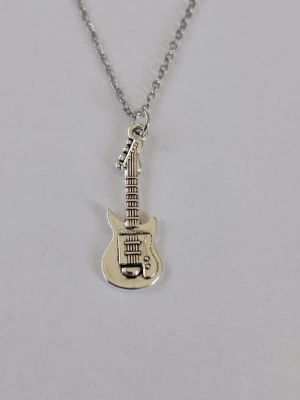 Halsband med elgitarr-hänge i silverfärg - Snyggt tunt halsband (ankarlänk) med ett detaljerat hänge i form av en elgitarr. Kedjan och hänget är i silverfärgad metall och passar perfekt för dig som gillar musik och vill ha en cool accessoar. Hänget har tydliga detaljer som strängar och knappar. Materialet rostfritt stål. 