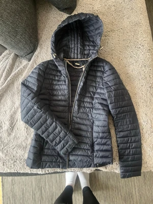 Mörkblå pufferjacka Massimo Dutti - Snygg mörkblå pufferjacka från Massimo Dutti med huva och dragkedja framtill. Jackan har quiltad design. Perfekt för våren och riktigt skön att ha. Säljer pga för liten för mig 